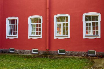 Fototapeta na wymiar white Windows on the red wall of the old house