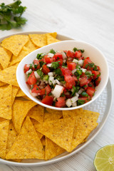 Pico de Gallo with gluten free tortilla chips on a white wooden background, side view. Close-up.