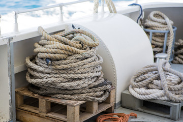 Close-up of a mooring rope with a knotted end tied around a cotter pin on a wooden pier. Nautical rope mooring
