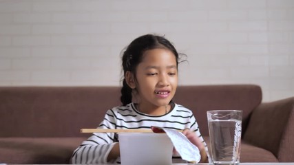 Little Asian girl eating hot and spicy instant noodle with happiness select focus shallow depth of field