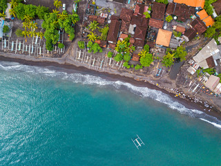 Aerial view of Amed beach in Bali, Indonesia. Traditional fishing boats called jukung on the black sand beach and one on the sea.