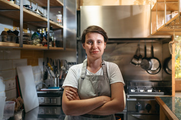 Female chef standing in her kitchen in a small italian style restaurant