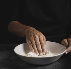 Close-up baker hand mixing flour