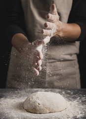 Close-up baker spreading flour on top of dough