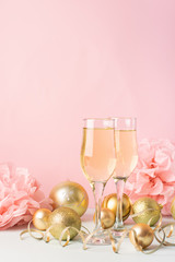 Champagne in glass goblets gold balloons stars serpentine a pastel delicate pink background. New year festive concept.