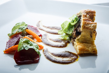 closeup trendy dish of baked in dough meat with mushrooms and spinach