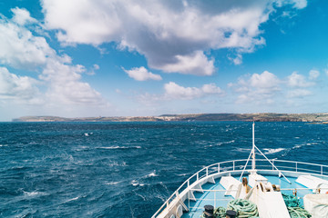 View from deck on ferry sailing across the Mediterranean sea to Gozo island, Malta. Cloudy sky and ...