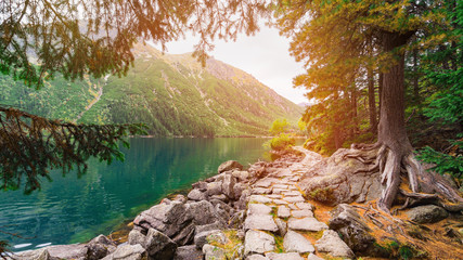Mountain landscape with hiking trail and view of wonderful  sunrise of Morskie Oko (Sea Eye) lake. Amazing morning view in High Tatras National Park, Poland, Europe.  Beauty of nature concept. © prystai