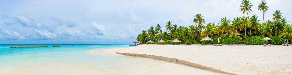 Beautiful sandy beach with sunbeds and umbrellas in Indian ocean, Maldives island
