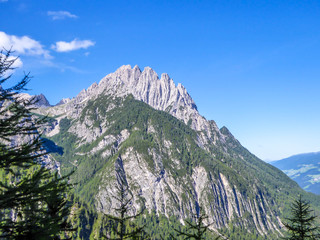 Massive, sharp stony mountain range of Lienz Dolomites, Austria. The mountain has a pyramid shape, it is partially overgrown with green bushes. Dangerous mountain climbing.Clear and beautiful day.