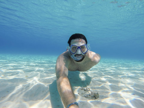 Young man swims in the sea - Millennial does snorkeling in the ocean in the summer