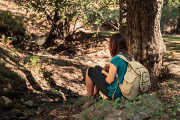 Naklejka premium Mother and daughter seating together on a stone in the forest
