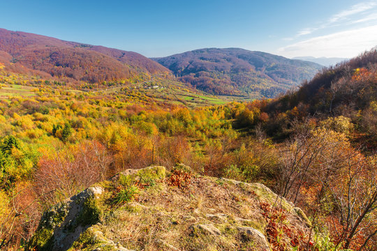 autumn scenery in mountains on a sunny day. view from a high vantage point in to the distant valley. trees in colorful foliage. rail station and viaduct in the distance. abandoned place