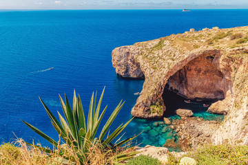 Blue Grotto in Malta. Pleasure boat with tourists runs. Natural arch window in rock