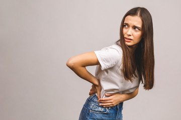 Unhappy woman suffering from backache isolated over grey background.