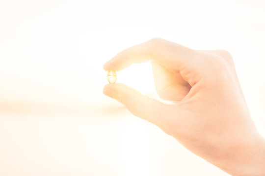 Gelatin Capsule With Vitamin D In Female Hands In The Sun. Vitamin D Deficiency Concept