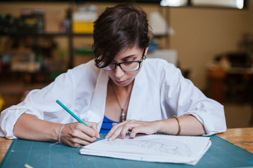 Young adult artist drawing a feather with a pencil