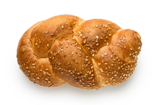 Plaited white bread roll with sesame seeds isolated on white. Top view.