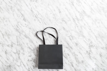 Black shopping bag on the marmol background for shopping concept. Copy space