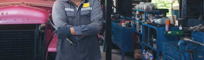 asia man in blue uniform car mechanic with wrench in garage. © sutlafk