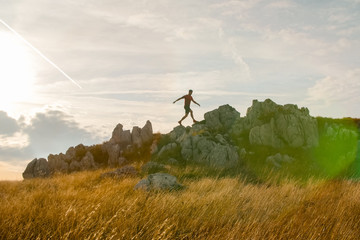 Fototapeta na wymiar Young man walking across the mountains ridge. Trail running preparations. Sunset