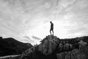 Young athletic man standing on the ridge. Trail running preparations for race.