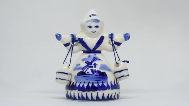 Delft Blue Figurine of girl carrying bells zoom in. Souvenir from Holland/Netherlands on isolated white background.