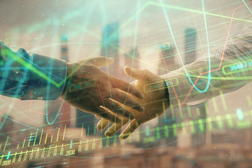 Double exposure of financial graph on cityscape background with two businessman handshake. Concept of stock market deal