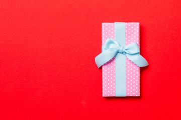 wrapped Christmas or other holiday handmade present in paper with blue ribbon on red background....