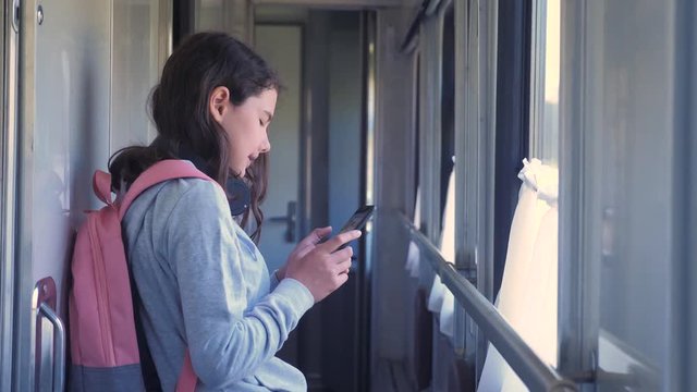 little girl walks on a train compartment car with a backpack and a smartphone. travel transportation railroad concept. the girl in the train at the window lifestyle corresponds the girl in the train