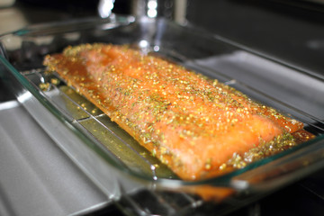 Marinated cedar plank salmon on a glass baking tray about to go in the oven.