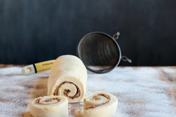 Homemade cinnamon roll dough over a floured surface with duster in background. Selective focus on...