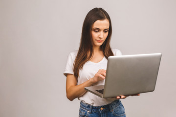 Naklejka premium Young beautiful woman in casual clothes holding laptop and sending email to her best friend isolated over grey background.