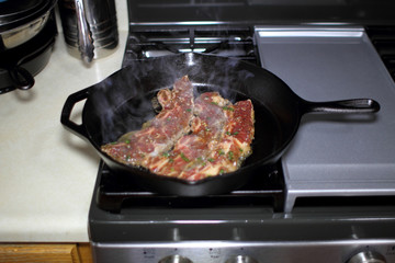 Korean style BBQ short ribs, known as Kalbi, on a cast iron skillet in a home kitchen.