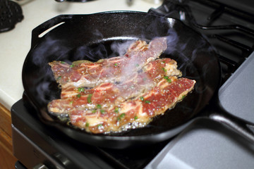 Korean style BBQ short ribs, known as Kalbi, on a cast iron skillet in a home kitchen.