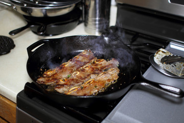 Korean style BBQ short ribs, known as Kalbi, on a cast iron skillet in a home kitchen.