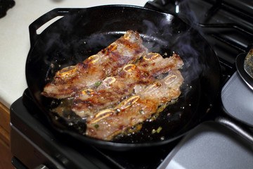 Korean style BBQ short ribs, known as Kalbi, on a cast iron skillet in a home kitchen.