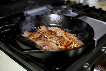 Korean style BBQ short ribs, known as Kalbi, on a cast iron skillet in a home kitchen.