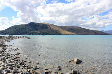 Bank of lake tekapo in new zealand with a mountain in the background