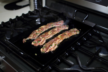 Korean style BBQ short ribs, known as Kalbi, on a cast iron skillet in a home kitchen.