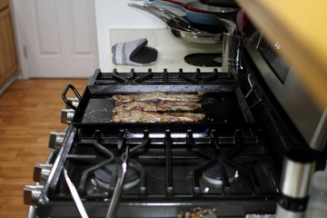 Korean style BBQ short ribs, known as Kalbi, on a carbon steel griddle in a home kitchen.