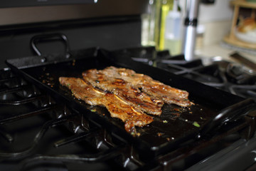 Korean style BBQ short ribs, known as Kalbi, on a carbon steel griddle in a home kitchen.