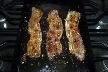Korean style BBQ short ribs, known as Kalbi, on a carbon steel griddle in a home kitchen.