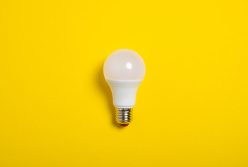LED lamp bulb idea on yellow background, top view
