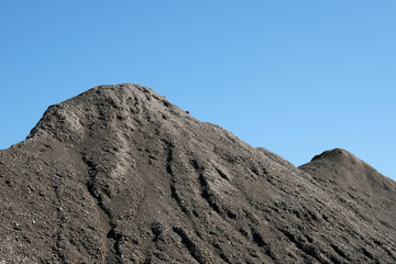Pile of grey ash material blue sky background