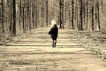 Little child runs along forest road between trees