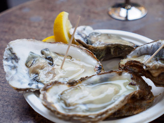 Closeup macro detail of a plate of raw oysters served with lemon. Borough Market, London, United Kingdom. Travel and cuisine.