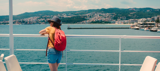 Girl leaning on metal fence at ferry looking at the sea