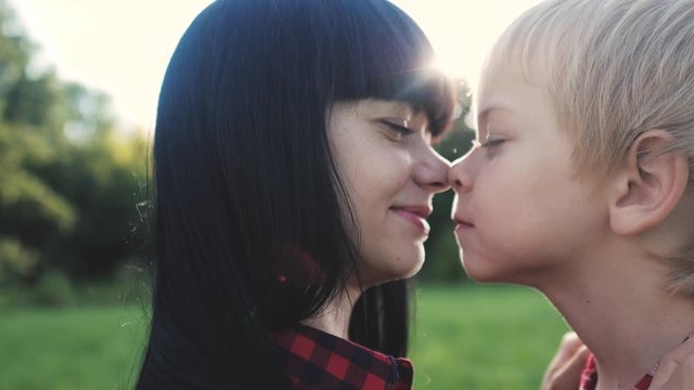 happy family mom and a son concept. son kisses mom tender childhood video. slow motion video. mom brunette girl gently hugs takes care of the boy son lifestyle blonde outdoors