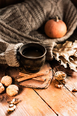 Autumn, fall leaves, a hot steaming cup of coffee and a warm sweater on a wooden table background. Seasonal, morning coffee, sunday relaxing and still life concept.Copy space.